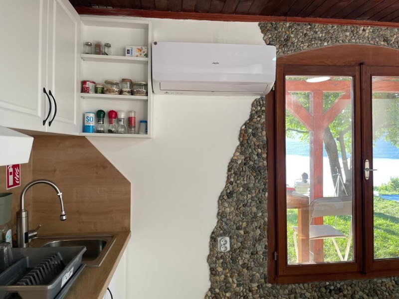 Kitchen unit with a sink next to a natural stone wall and a window onto the veranda