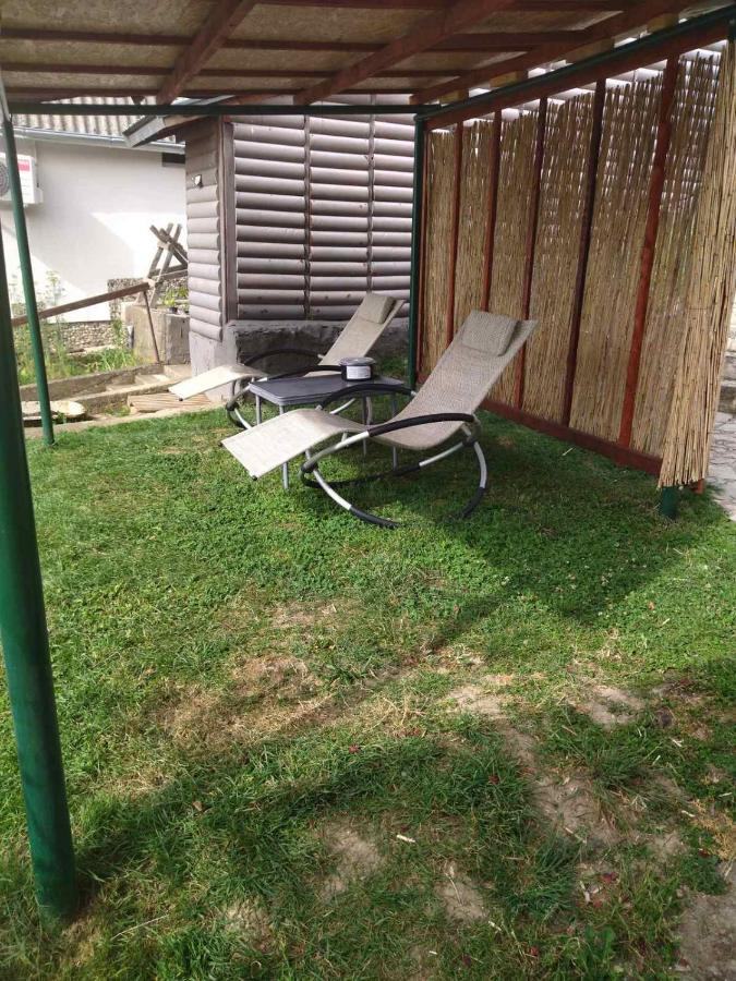 Two sun loungers on the lawn under a pergola of wood and reed