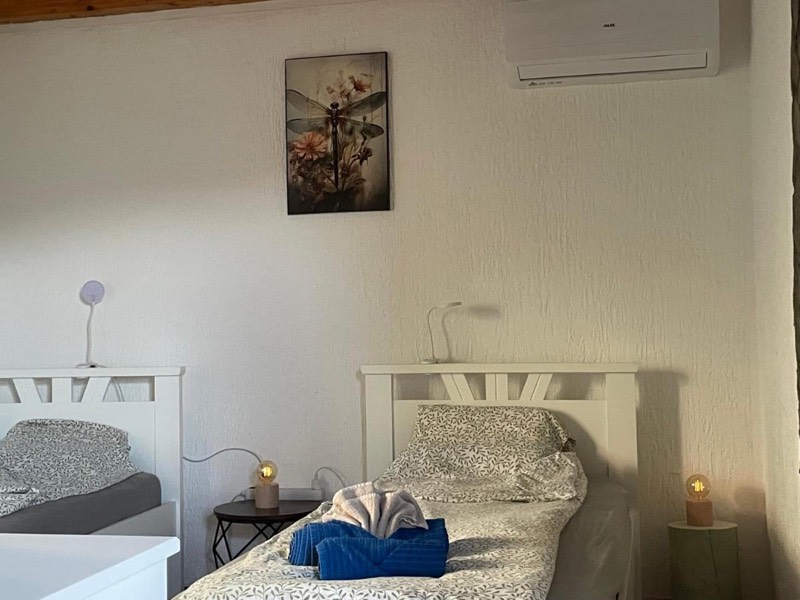 Bedroom with two single beds, bedside lamps, a picture on the wall and air conditioning