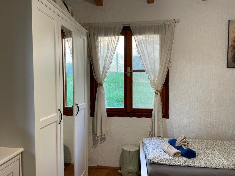 Bedroom window with a wooden frame and curtains, a bed in front of it